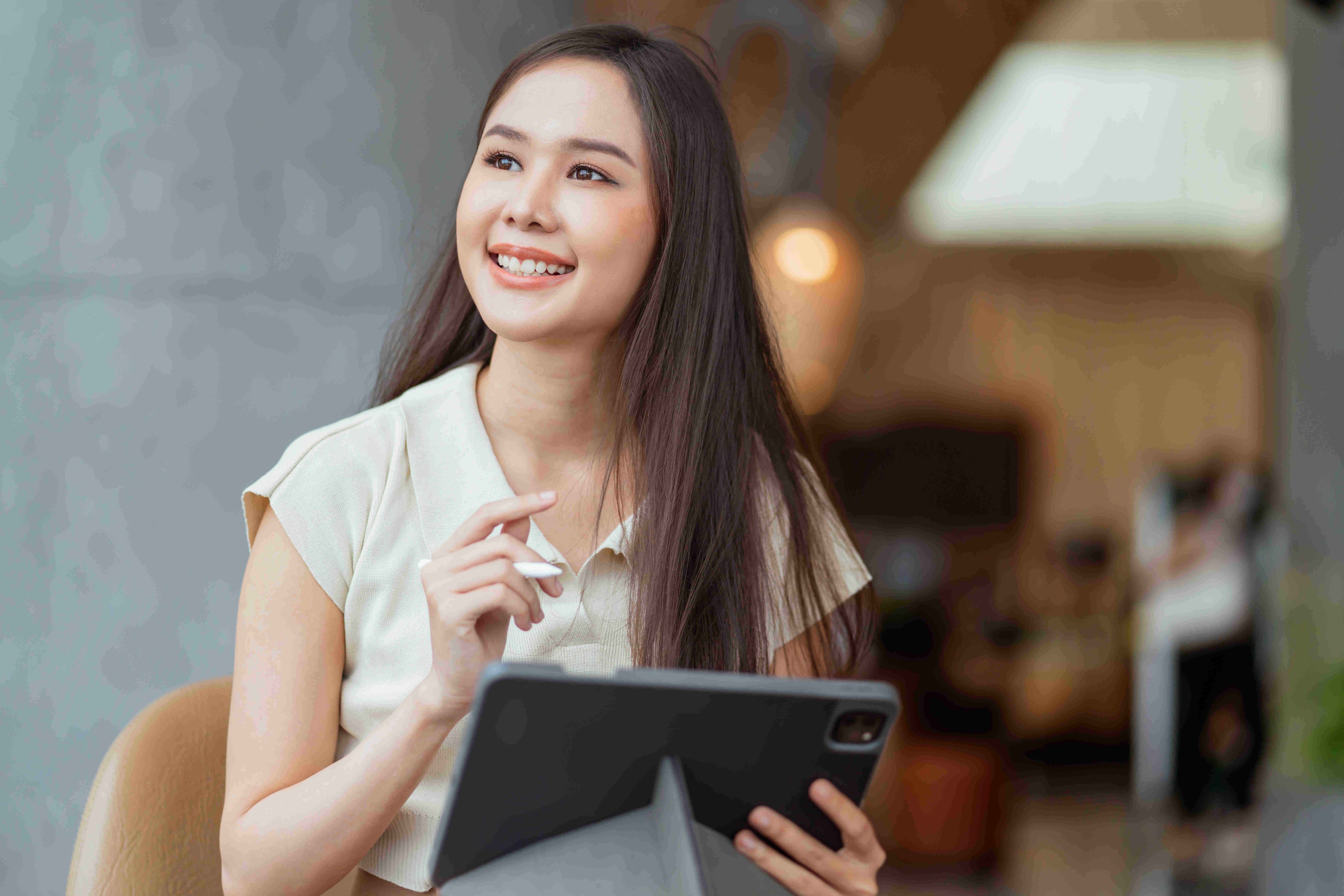 asian female freelance digital nomad career happiness workation cheerful smiling working online with smart device tablet smartphone abroad occupation project work anywhere new frameless lifestyle cafe